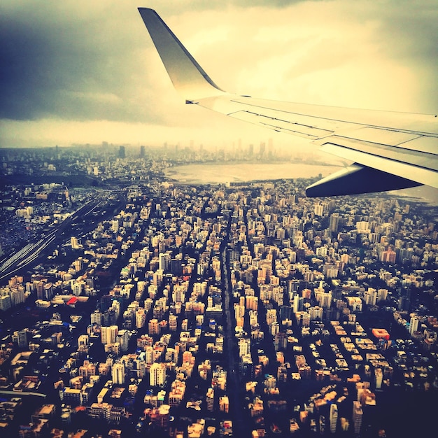 Photo cropped image of airplane over cityscape