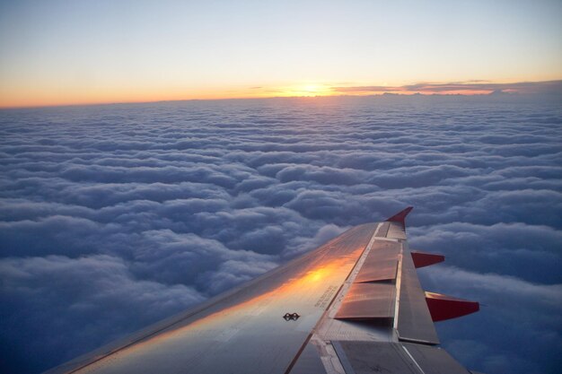 Immagine ritagliata di un aereo che vola sopra un paesaggio nuvoloso durante il tramonto