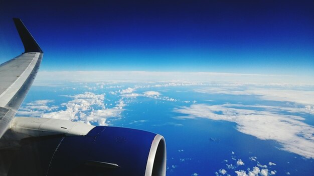 Cropped image of airplane flying over sea against blue sky