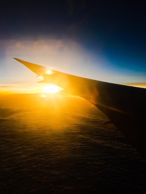 Photo cropped image of airplane flying over sea during sunset