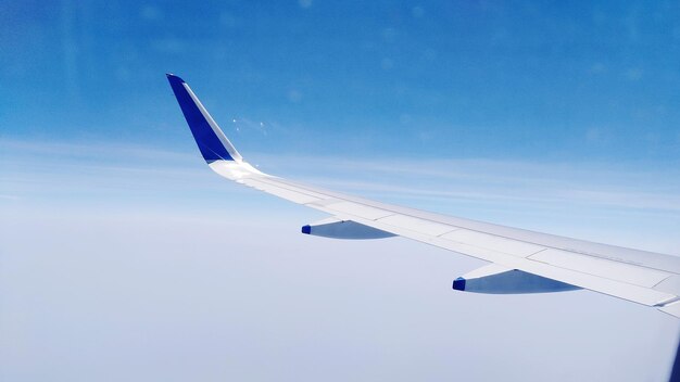 Photo cropped image of airplane wing against blue sky