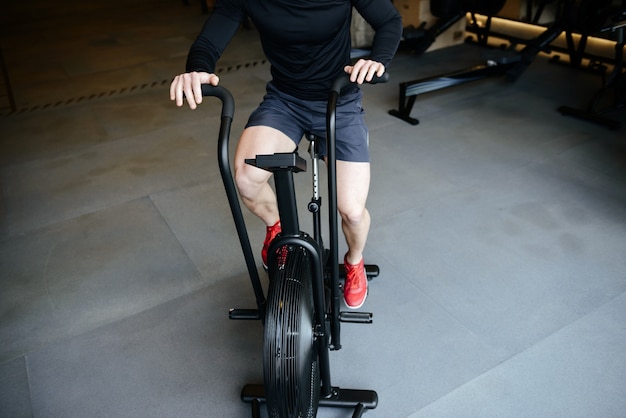 Cropped image of Athletic man using spinning bicycle