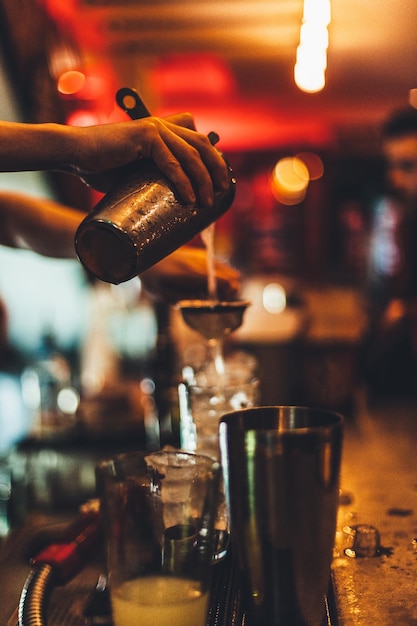 Foto immagine ritagliata di un barista che fa un cocktail in un bar