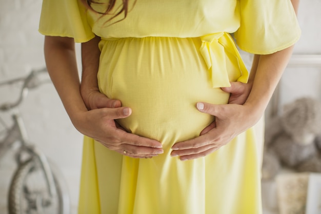 Cropped image of beautiful pregnant woman and her handsome husband hugging the tummy