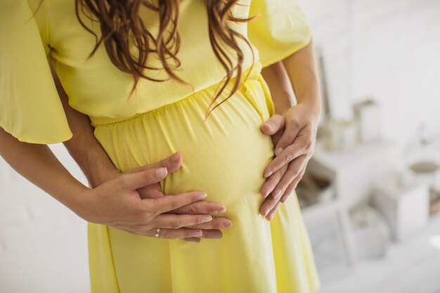 Cropped image of beautiful pregnant woman and her handsome husband hugging the tummy