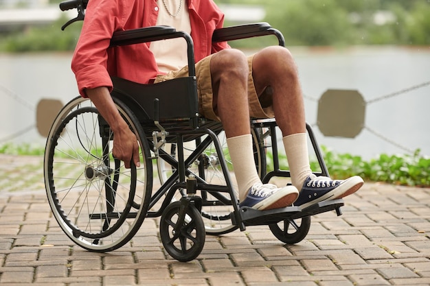 Cropped image of Black man moving around city in wheelchair