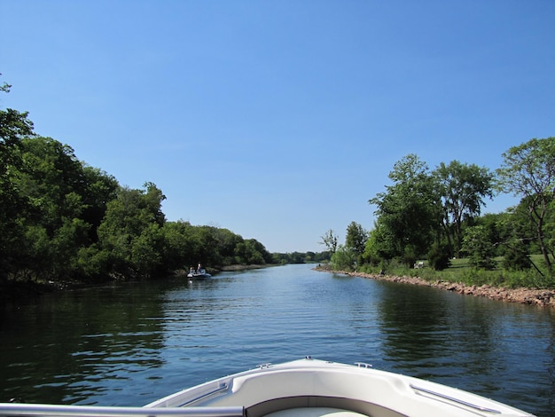 Cropped image of boat sailing in river against clear blue sky