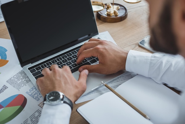 Cropped image of business adviser working with laptop at table in office