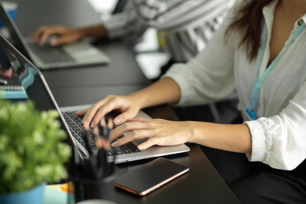 Cropped image of business workers typing and working on laptop computer at her workplace.