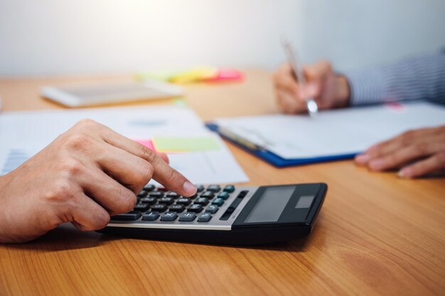 Cropped image of businessman using calculator on table