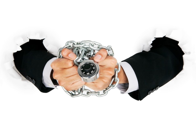 Photo cropped image of businessman with chains and lock on hand coming out from torn paper