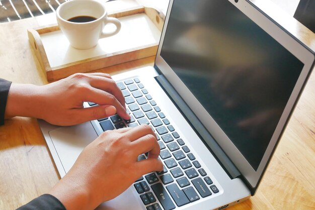 Cropped image of businesswoman using laptop at desk in office