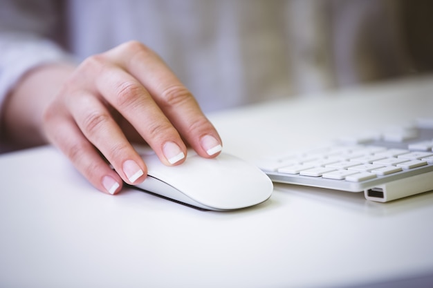 Cropped image of businesswoman using mouse on desk at office