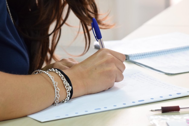 Photo cropped image of businesswoman writing in book at office