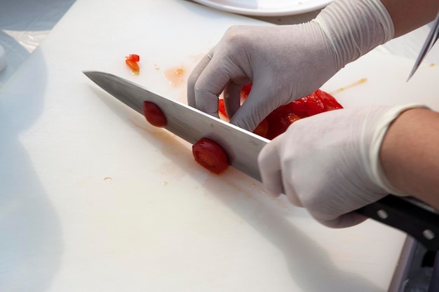 Photo cropped image of chef cutting tomato on board