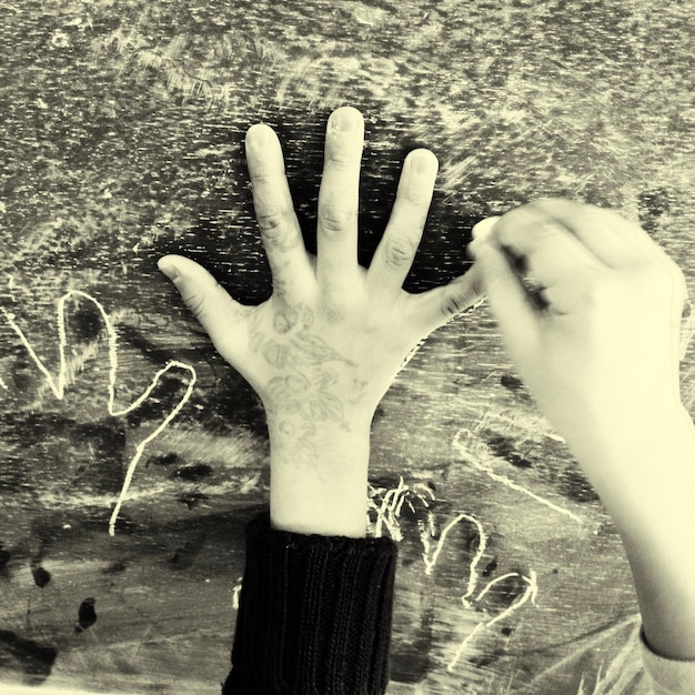 Photo cropped image of children drawing around hand on blackboard