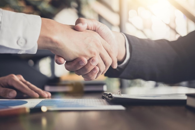 Cropped image of colleagues shaking hands over desk