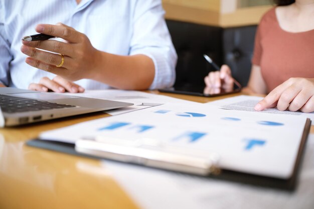 Cropped image of colleagues working over graphs in office