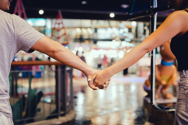 手を繋いでいるとショッピングモールで野外を歩いているカップルのトリミングされた画像