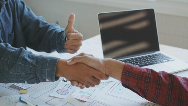 Photo cropped image of coworkers shaking hands over papers