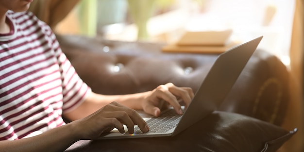 Photo cropped image of creative man using typing on computer laptop.