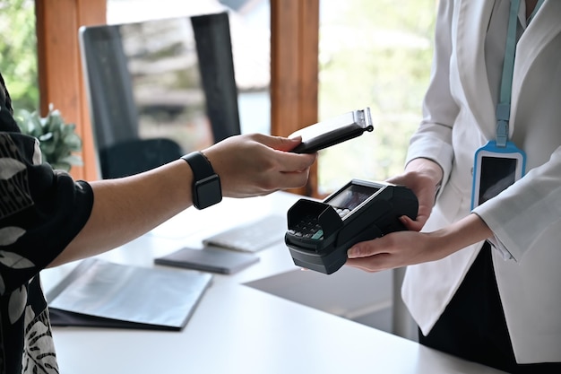 Cropped image of customer using smart phone scanning for contactless payment