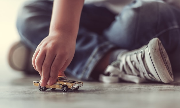 Cropped image of cute little boy playing with toy car.