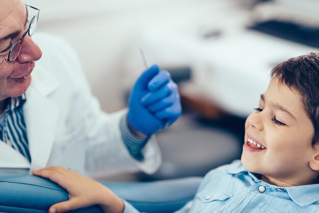 Photo cropped image of dentist examining boy at clinic