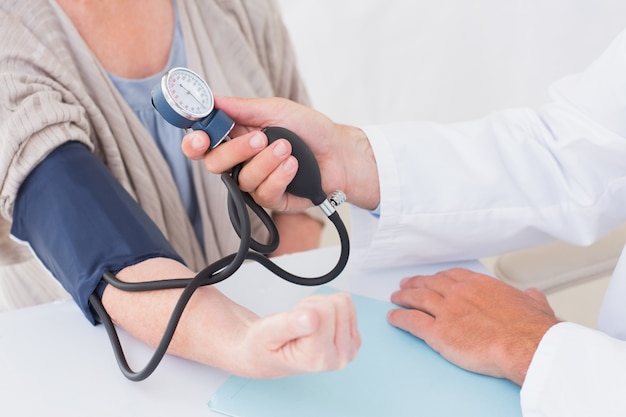 Cropped image of doctor checking patients blood pressure