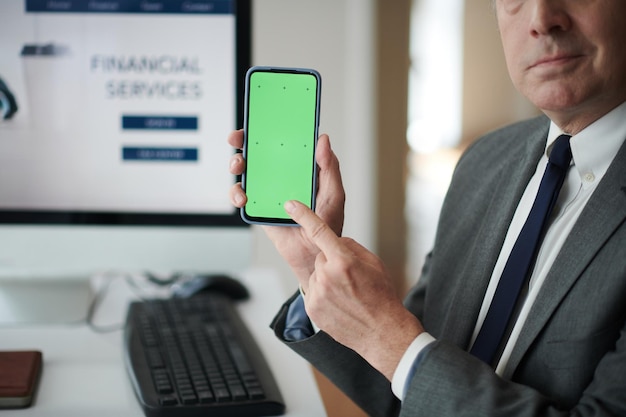 Cropped image of entrepreneur pointing at smartphone with green screen