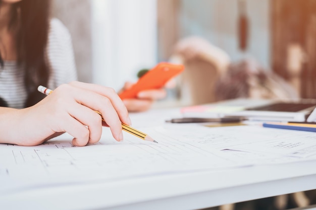 Cropped image of female architect working on blueprint at workshop