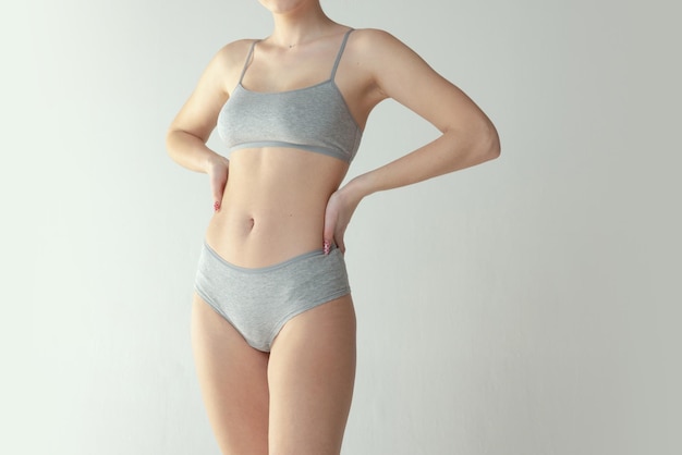 회색 스튜디오 배경에 격리된 면 속옷을 입은 여성의 몸을 자른 이미지