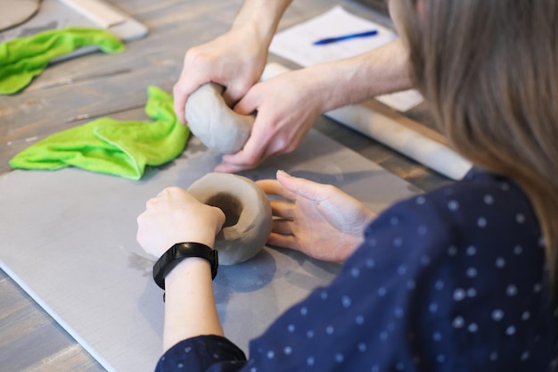 Foto immagine ritagliata del vasaio femminile che scolpisce il vaso di terracotta con le mani la donna ceramista lavora con la terracotta grezza creando ceramiche fatte a mano luogo di lavoro del maestro della ceramica artigianato e concetto di piccola impresa