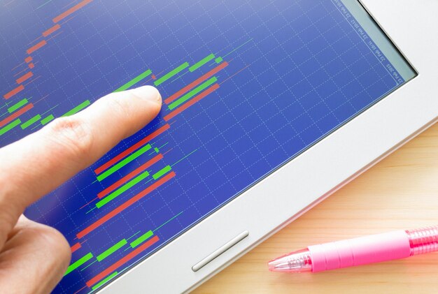 Photo cropped image of finger pointing at chart on digital tablet