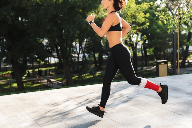 屋外で走っているスポーツウェアを着ているフィットネス女性のトリミングされた画像