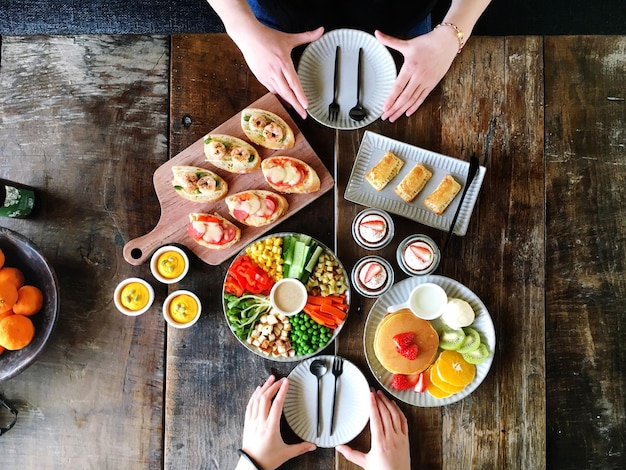 木製のテーブルで食べ物を食べている友人のカットされた画像