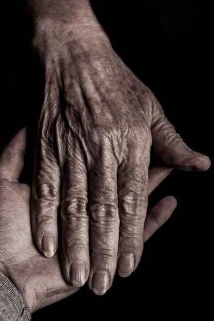 Cropped image of friends holding hands against black background