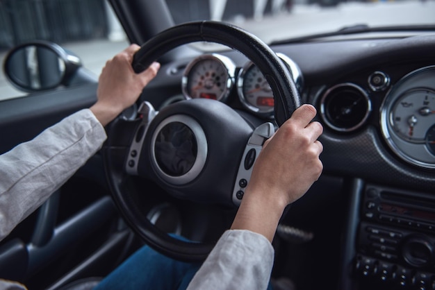 Photo cropped image of girl driving a car hands on steering wheel