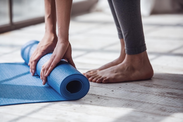 Photo cropped image of girl rolling yoga mat