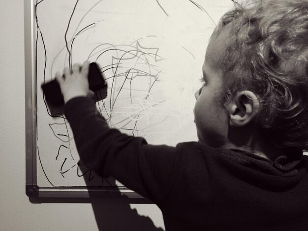 Cropped image of girl scribbling on white board