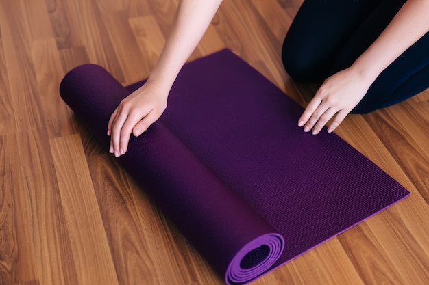 Cropped image girl unrolling a yoga mat for training at home