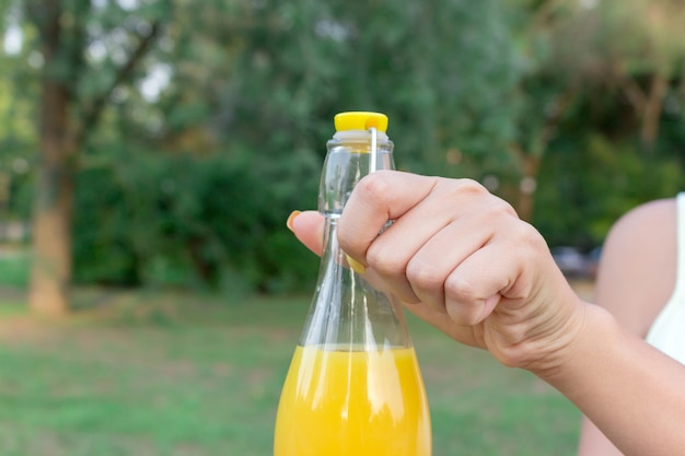 Cropped image of girl who is holding a bottle of juice outside