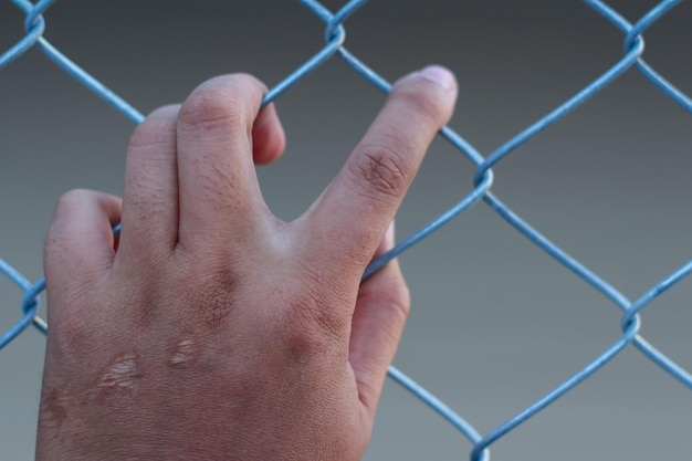 Обрезанное изображение руки на цепном заборе