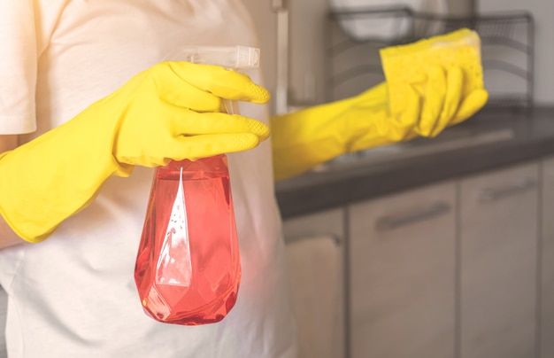 Foto immagine ritagliata delle faccende domestiche per la pulizia delle mani, messa a fuoco selettiva per la mano nei guanti e attrezzatura per il lavaggio