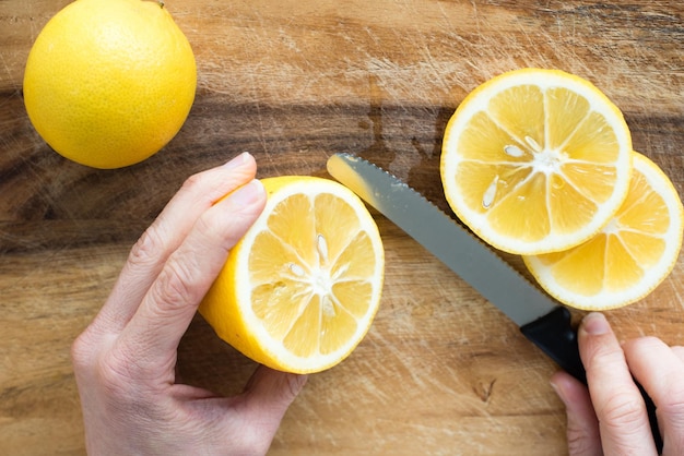 Photo cropped image of hand cutting lemon on cutting board