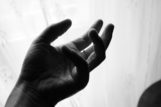 Photo cropped image of hand gesturing against curtain