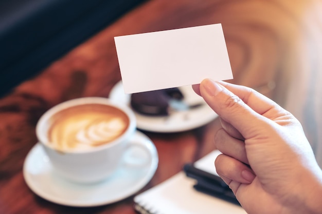 cropped image of hand holding coffee cup on table