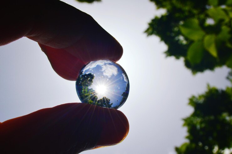 Photo cropped image of hand holding crystal ball against sky