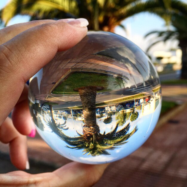 Foto immagine ritagliata di una mano che tiene una palla di cristallo con riflesso