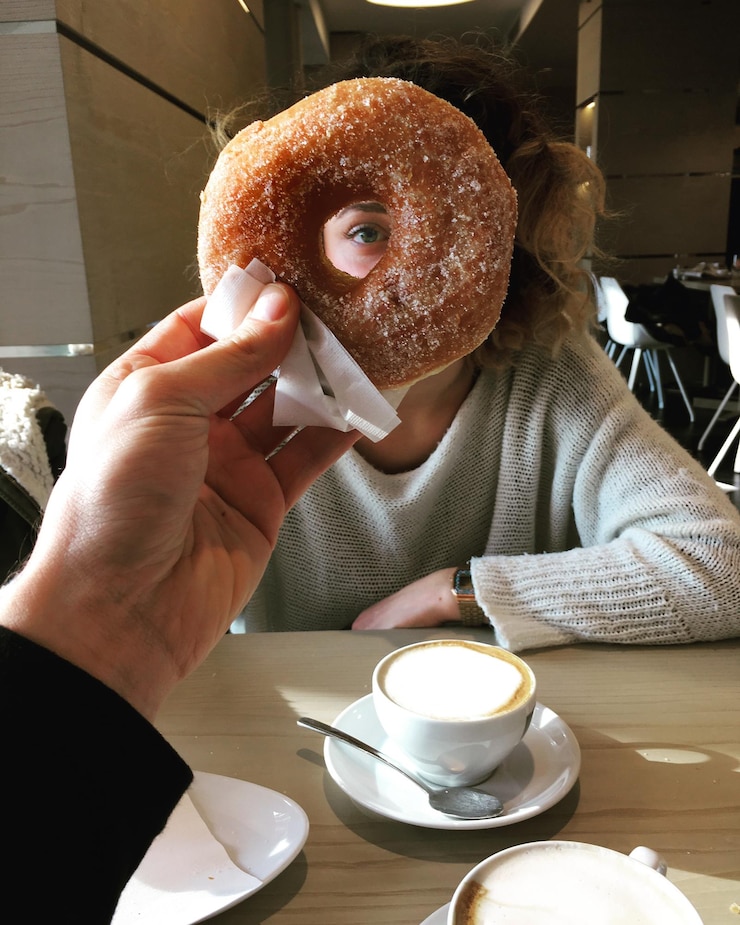 Photo cropped image of hand holding donut against woman face